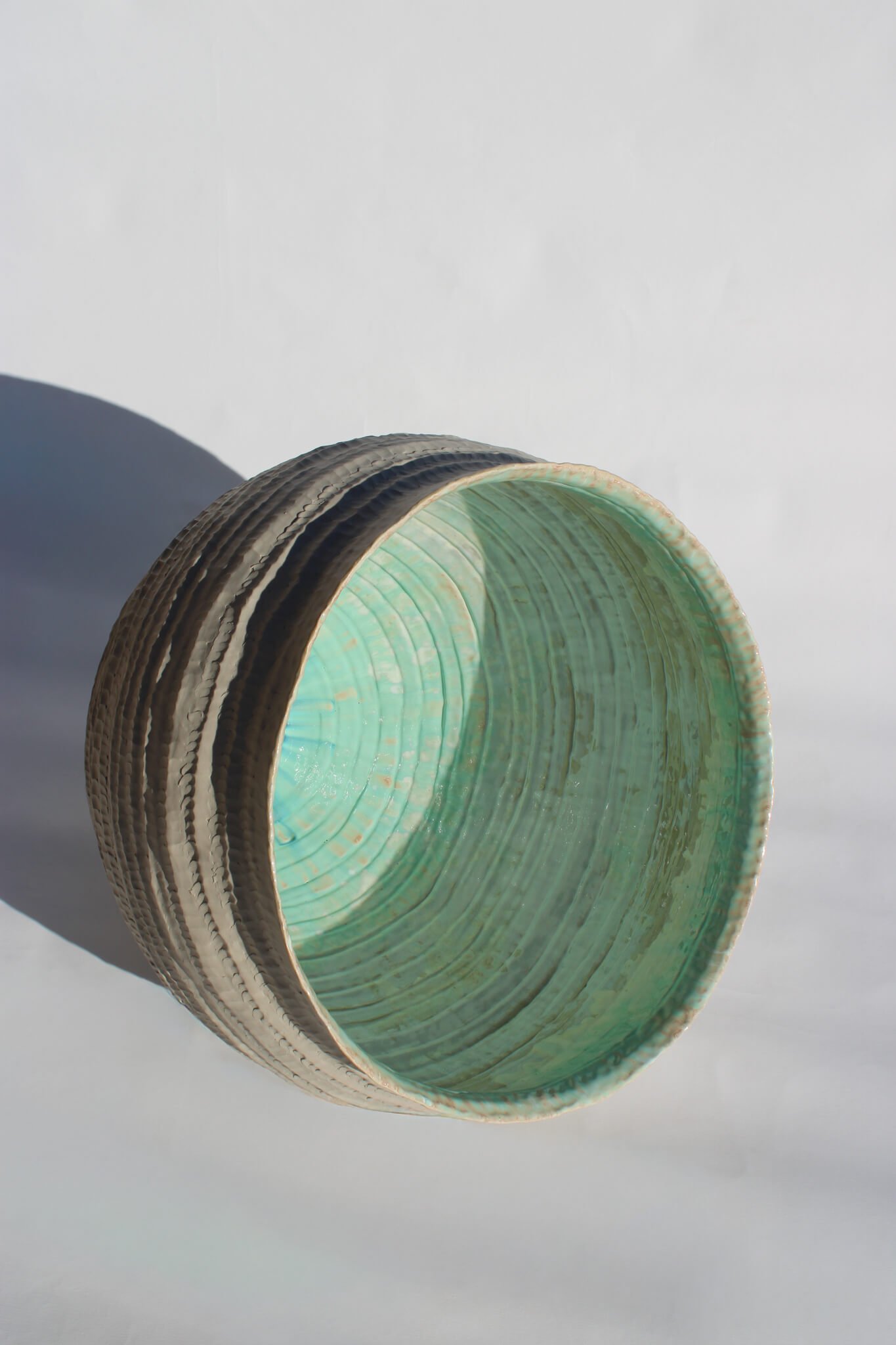 Side view of the reclined Primordial Vessel: a giant ceramic vessel sculpted out of ivory stoneware clay and containing crystalline glaze by multidisciplinary artist Noemie Marmara