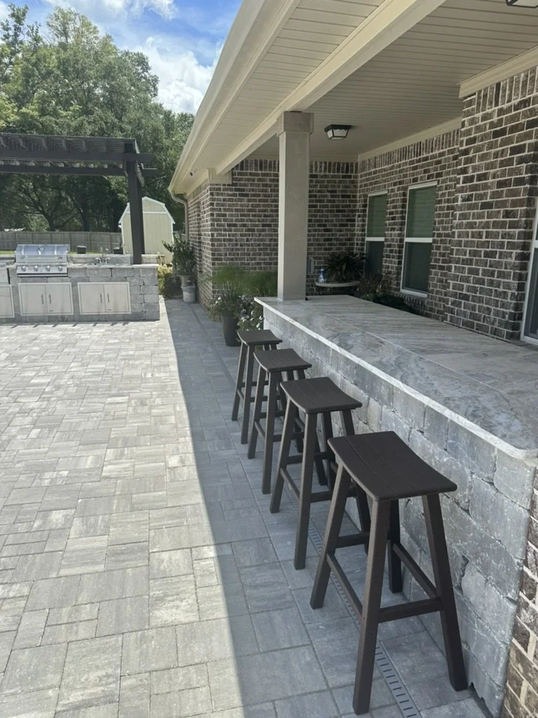 Outdoor bar area: Stylish patio with bar seating and durable stone paver flooring.