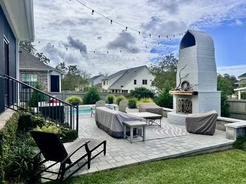 Poolside elegance: Cozy poolside lounge with beautiful paver flooring and outdoor fireplace.