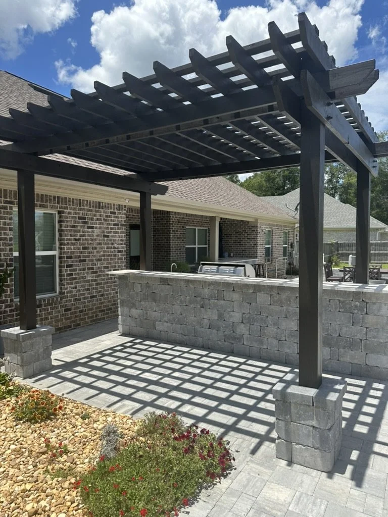 Pergola-covered outdoor bar with premium stone finishes and vibrant landscaping.