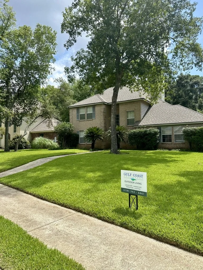 Professional landscaping with healthy lawn, Gulf Coast Sodscapes sign, and attractive curb appeal.
