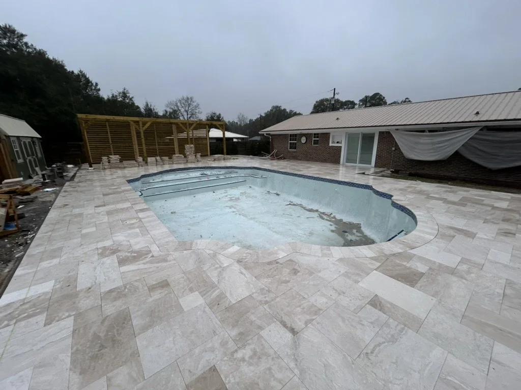 Custom pool with high-end travertine pavers, pergola, and sophisticated backyard design.