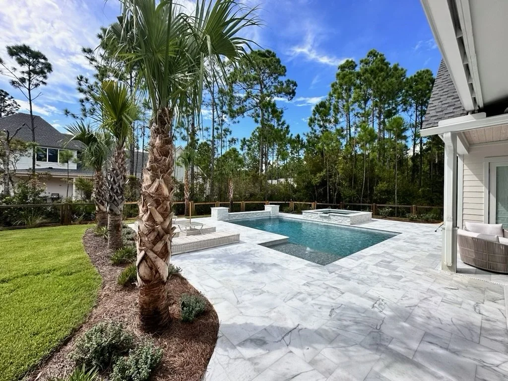 Tropical landscaping with palm trees beside a luxurious pool in the Gulf Coast region