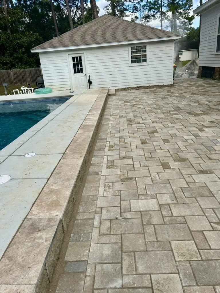 Clean paver pool deck with functional design, enhancing a bright backyard setting.