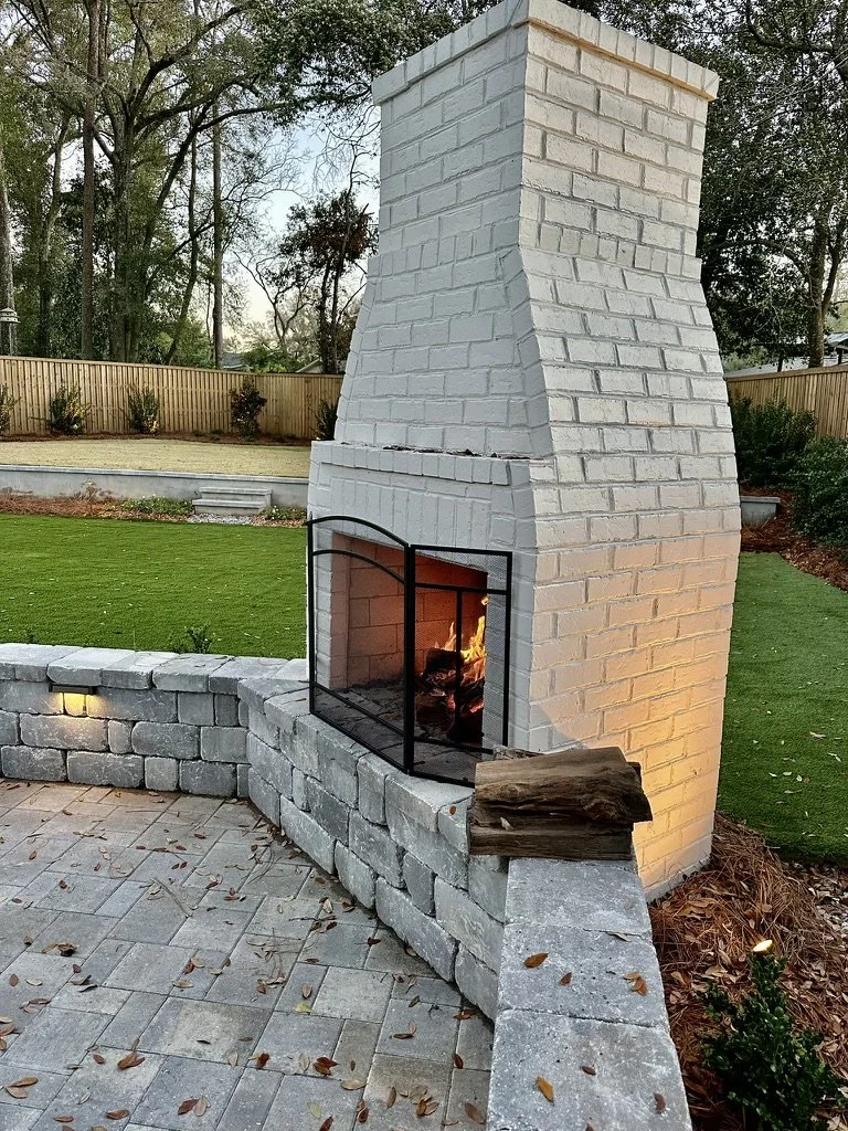 Stunning white stone outdoor fireplace complemented by a clean paver patio design.