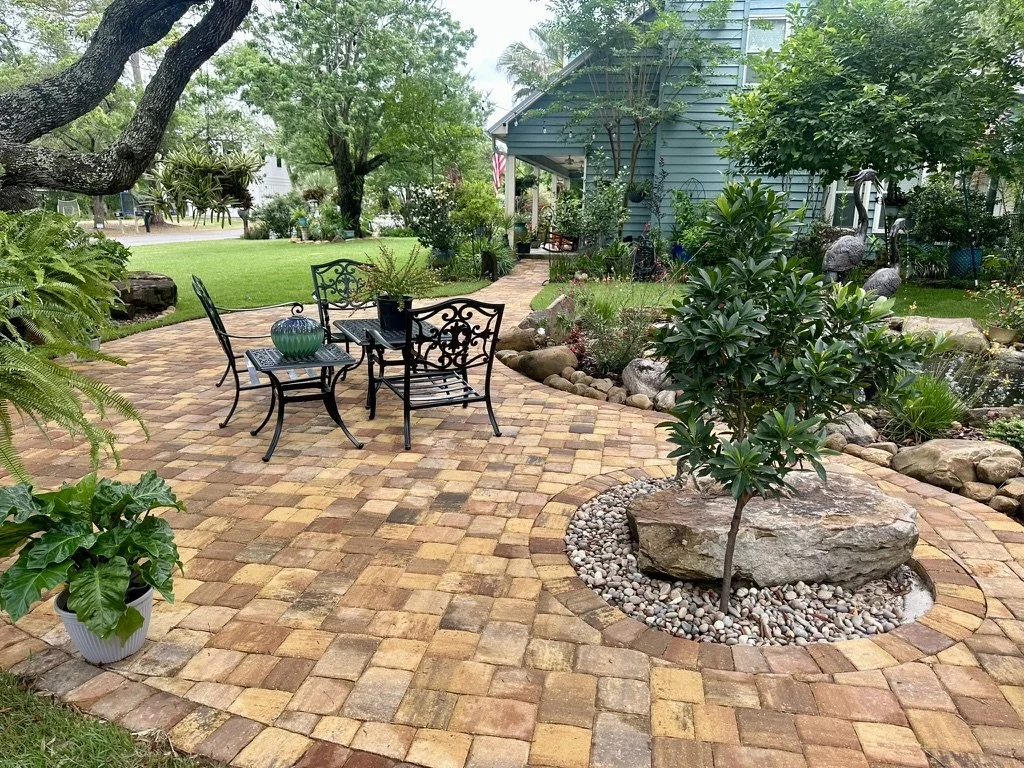 Cozy paver patio surrounded by greenery, featuring comfortable seating and decorative accents.