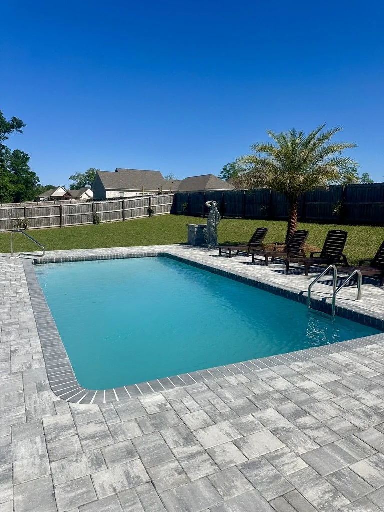 Luxurious pool area with modern pavers, palm trees, and a relaxing atmosphere.