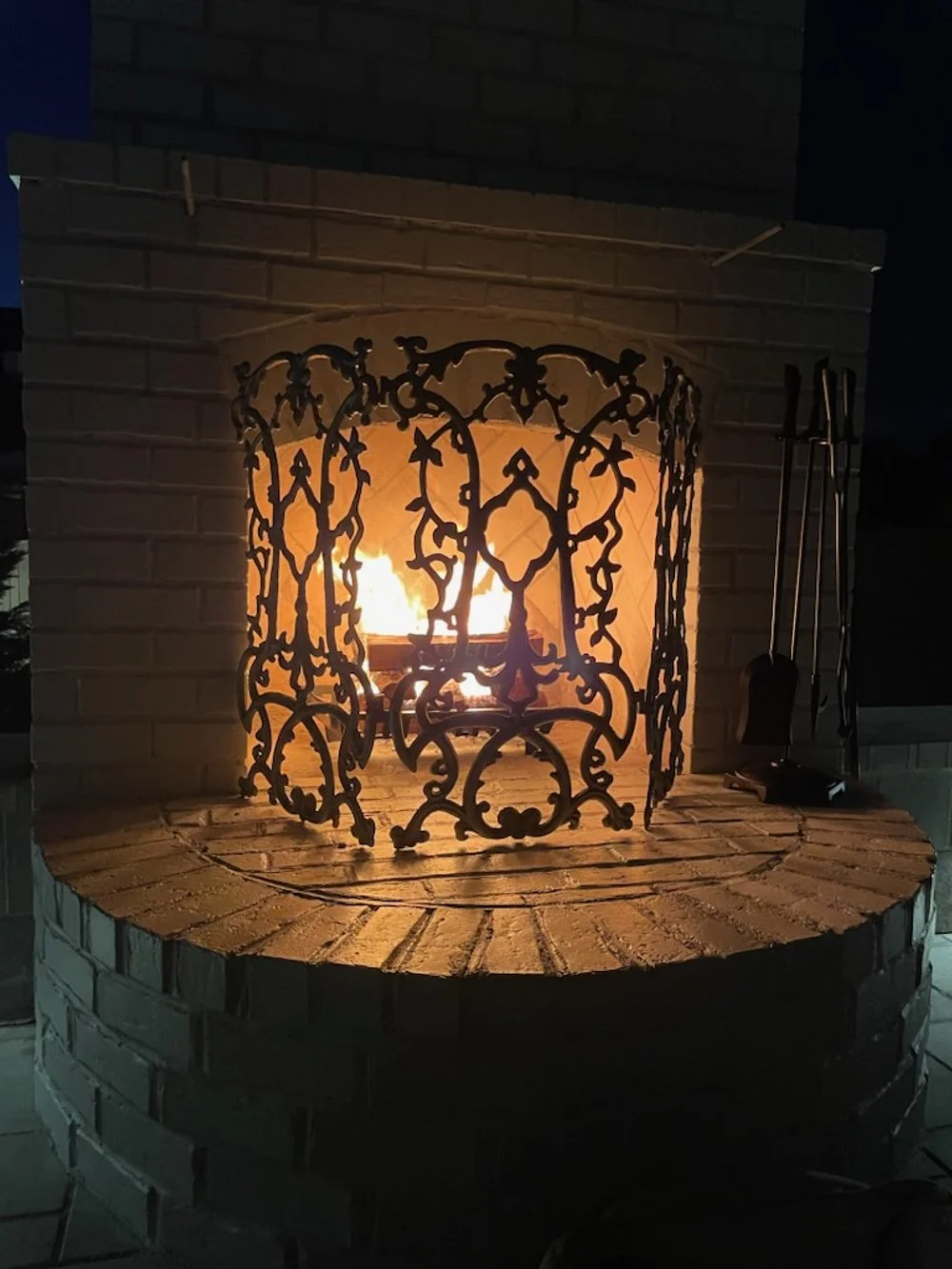 Beautifully crafted outdoor fireplace with intricate metal grate for charm.