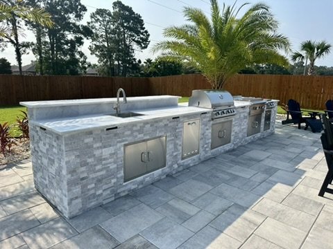  Luxurious stone outdoor kitchen featuring palm landscaping and premium stainless-steel appliances