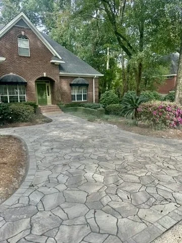 Stunning driveway with stamped concrete, leading to a charming brick home.