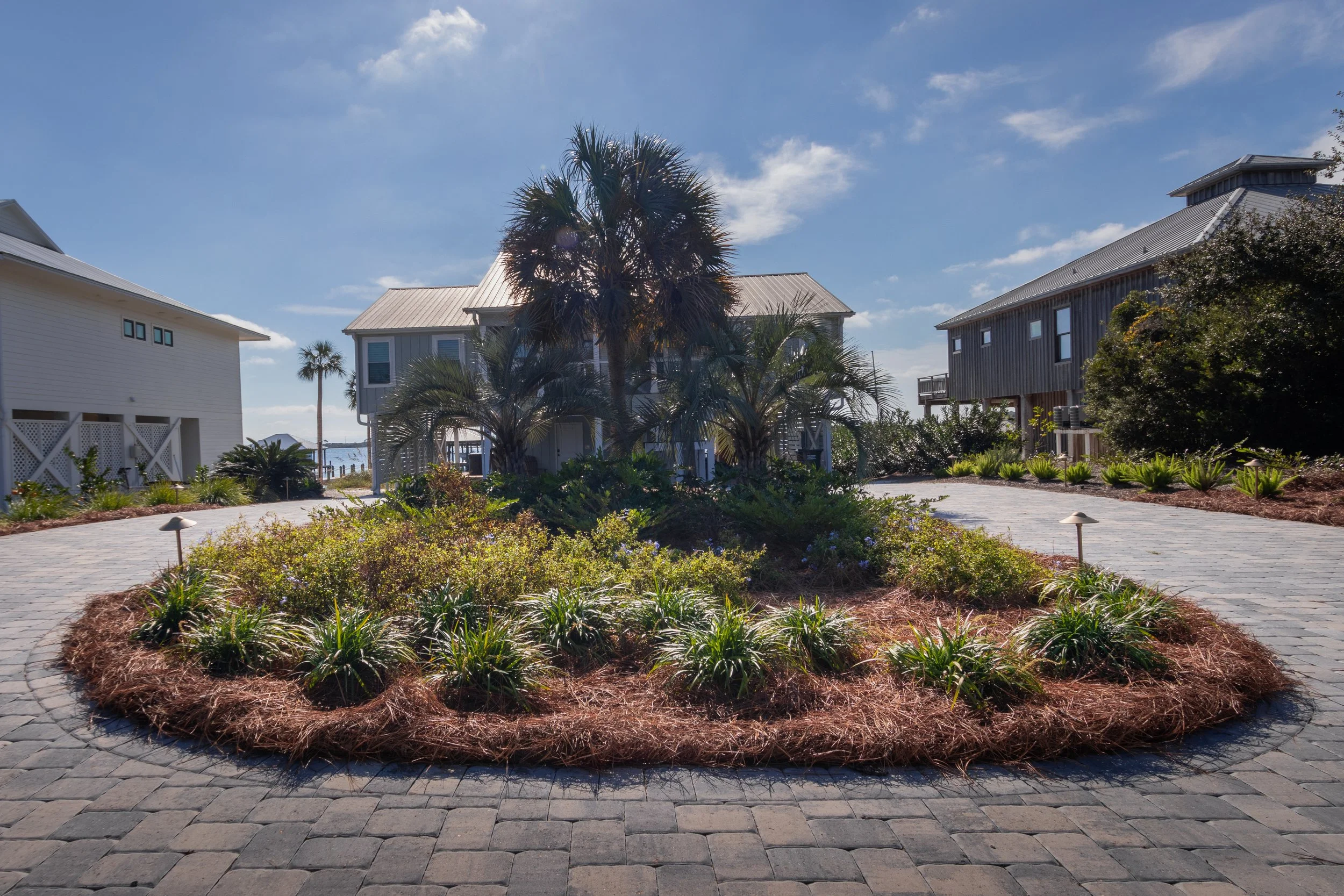 Coastal driveway landscaping with lush greenery and pavers leading to a home by the Gulf Coast