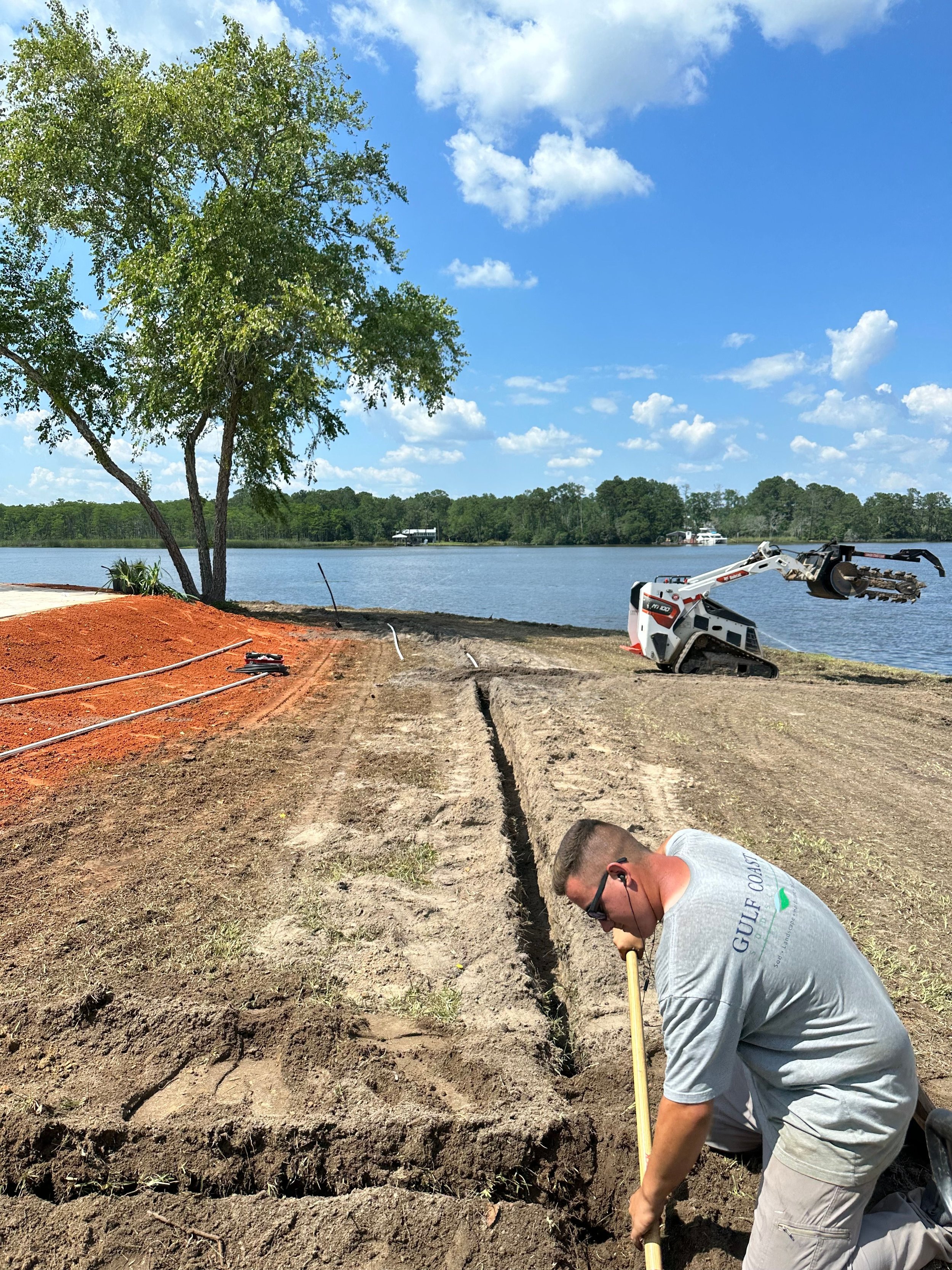 Irrigation technician installing a new irrigation system by a waterfront property in the Gulf Coast area.