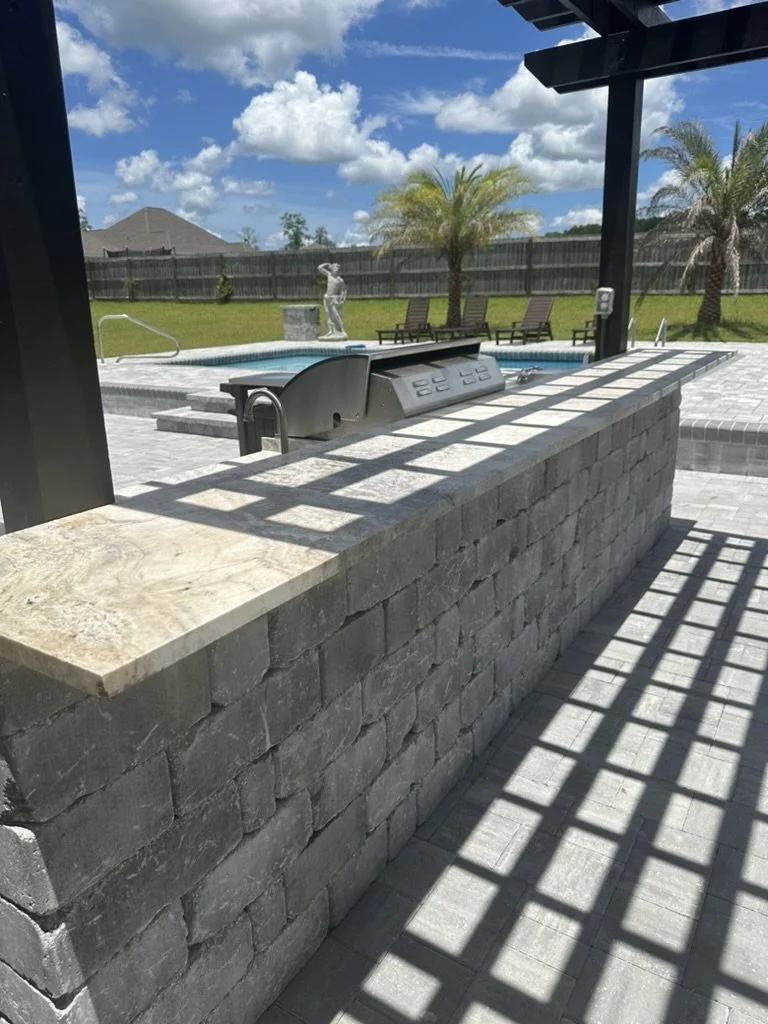 Elegant outdoor kitchen counter under pergola with spacious entertaining area.