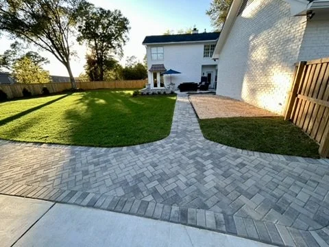 Stunning backyard design with paver pathways, green grass, and functional entertainment spaces.
