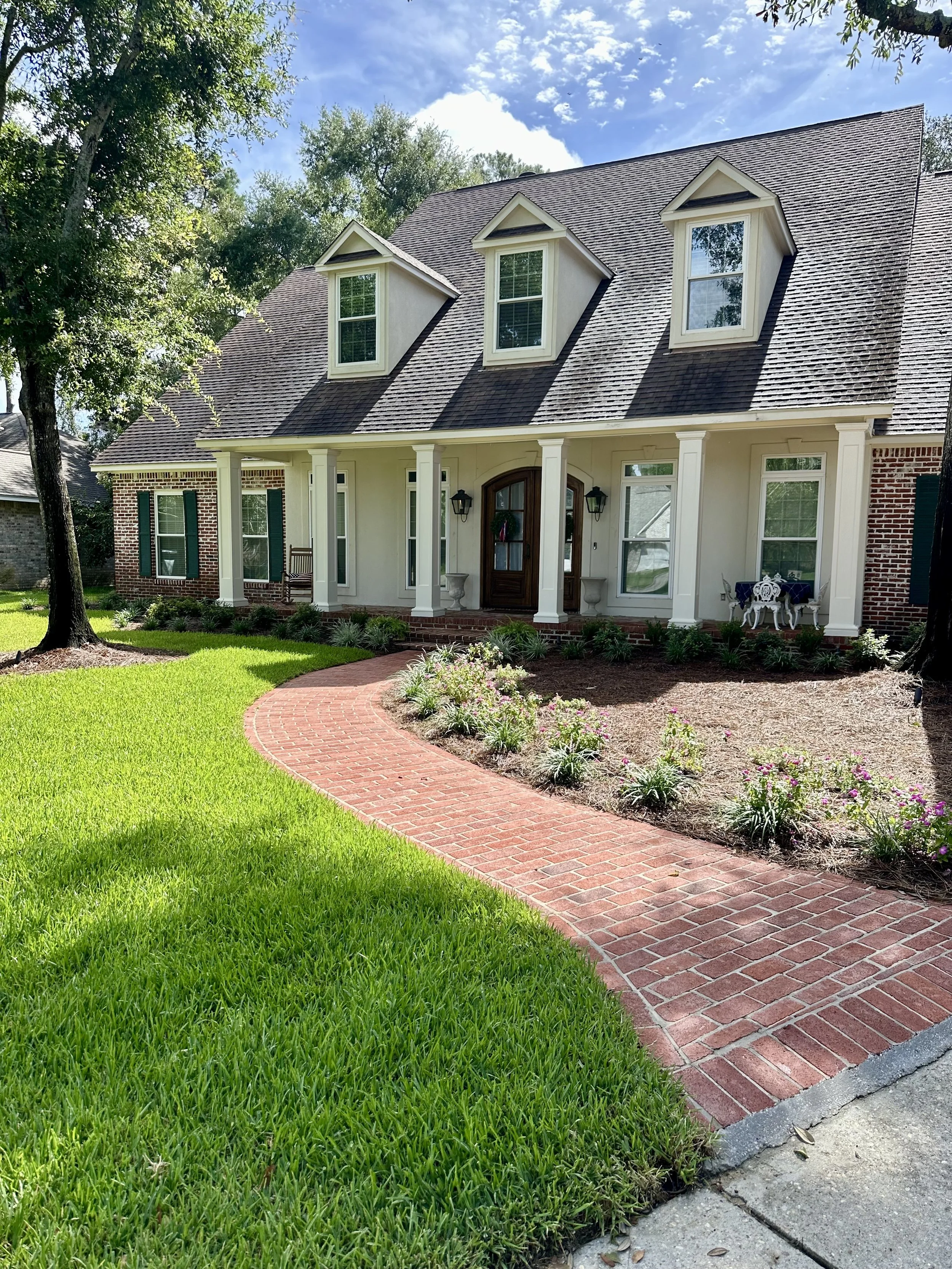 Beautifully landscaped front yard with brick walkway and manicured lawn