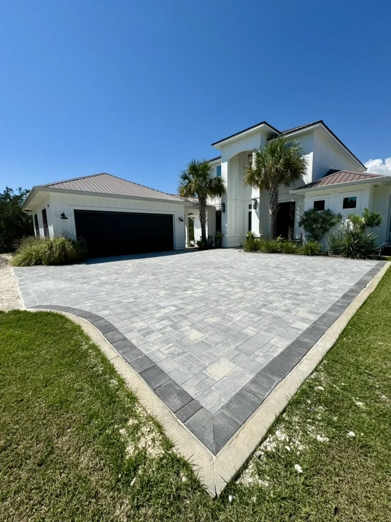 Modern paver driveway with contrasting border design, complementing a beautiful coastal home.