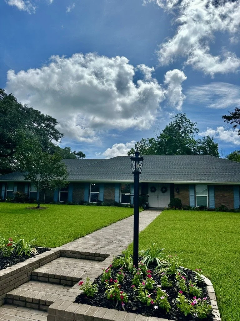 Beautiful brick walkway, vibrant flowers, lush grass, and charming front yard landscaping.