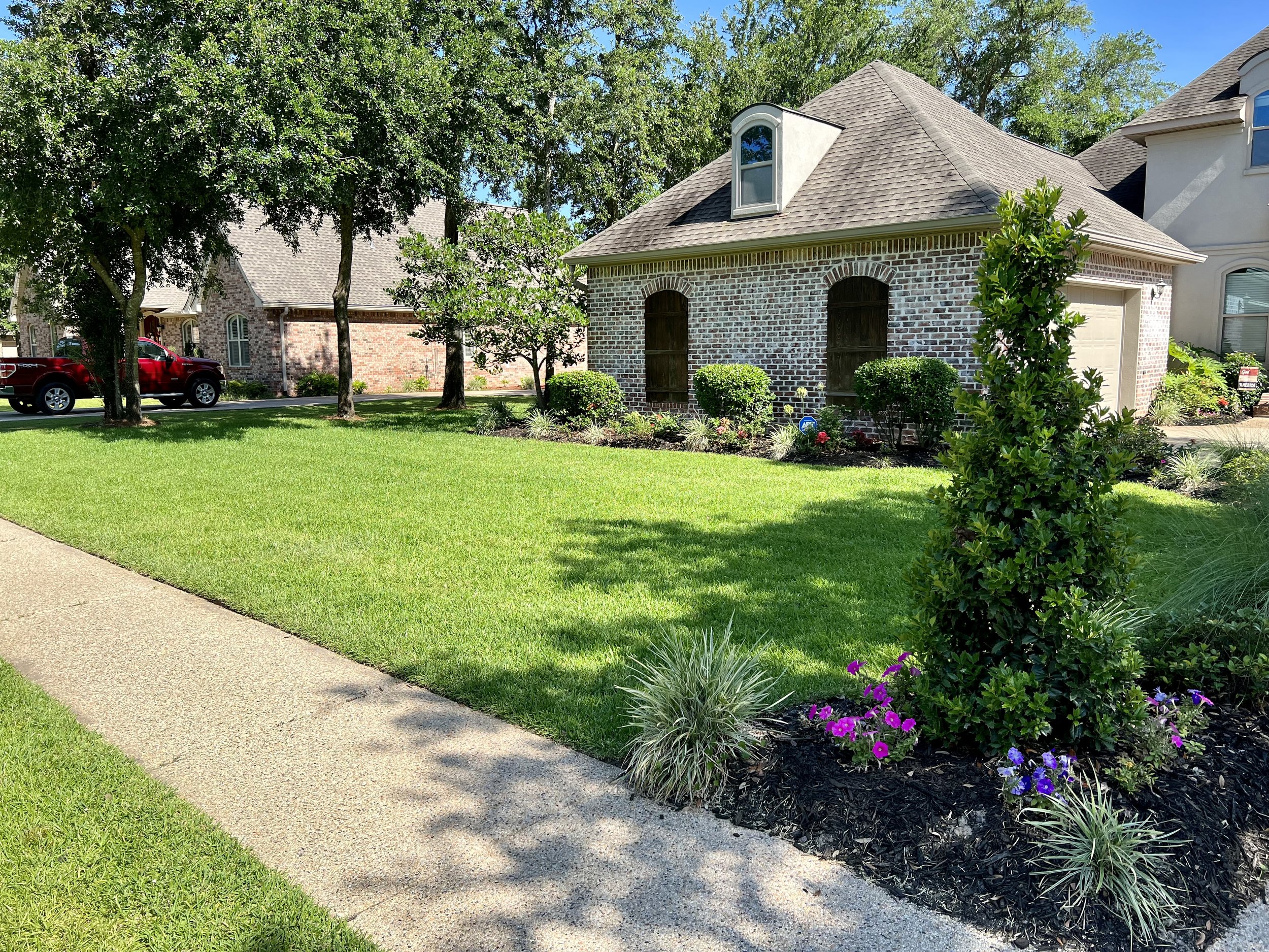 Landscaped garden with vibrant plants next to a garage in a Southern-style home