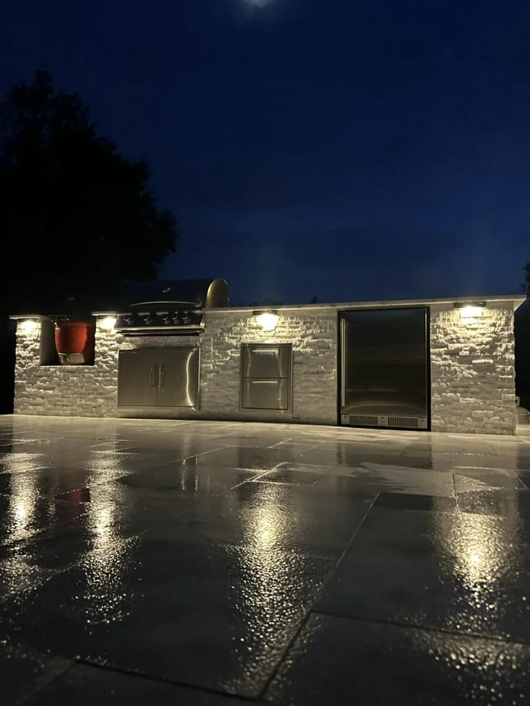Elegant outdoor kitchen with modern lighting, perfect for evening gatherings and grilling.