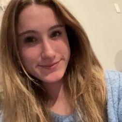 A young woman with long, wavy hair smiling at the camera