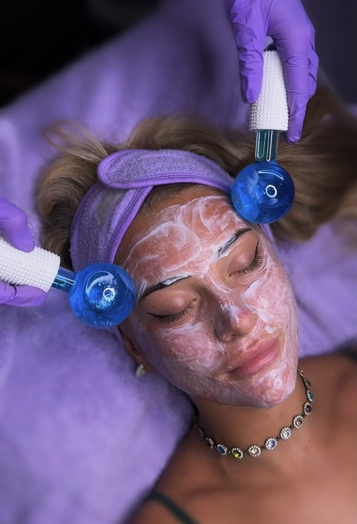 woman receiving an anti ageing advanced skin treatment with cooling ice globes, specialised face mask on face, hygienic gloves