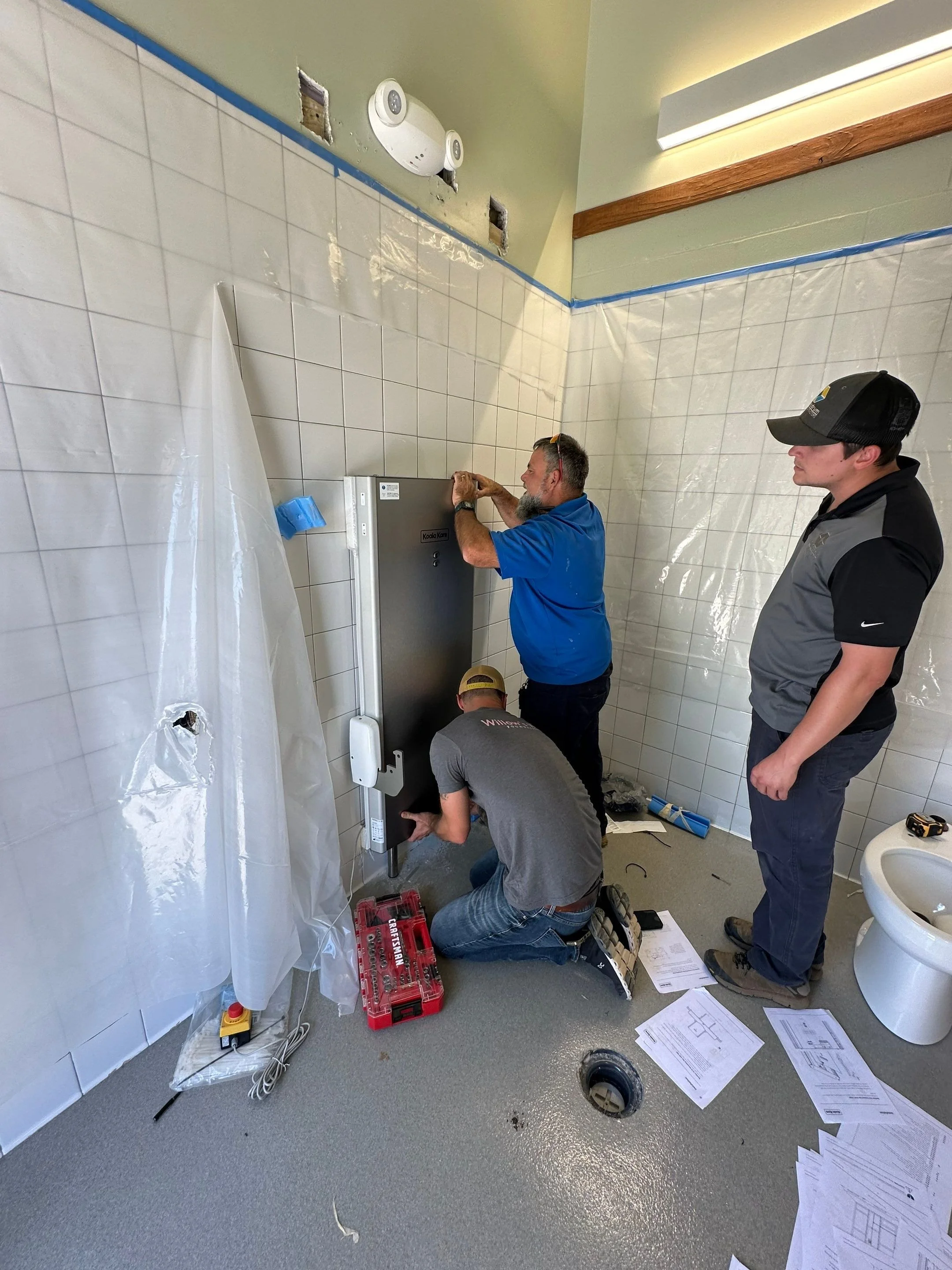 Concord, NC park bathroom getting a new powered changing table installed with three volunteers from Willow's Wish Foundation.