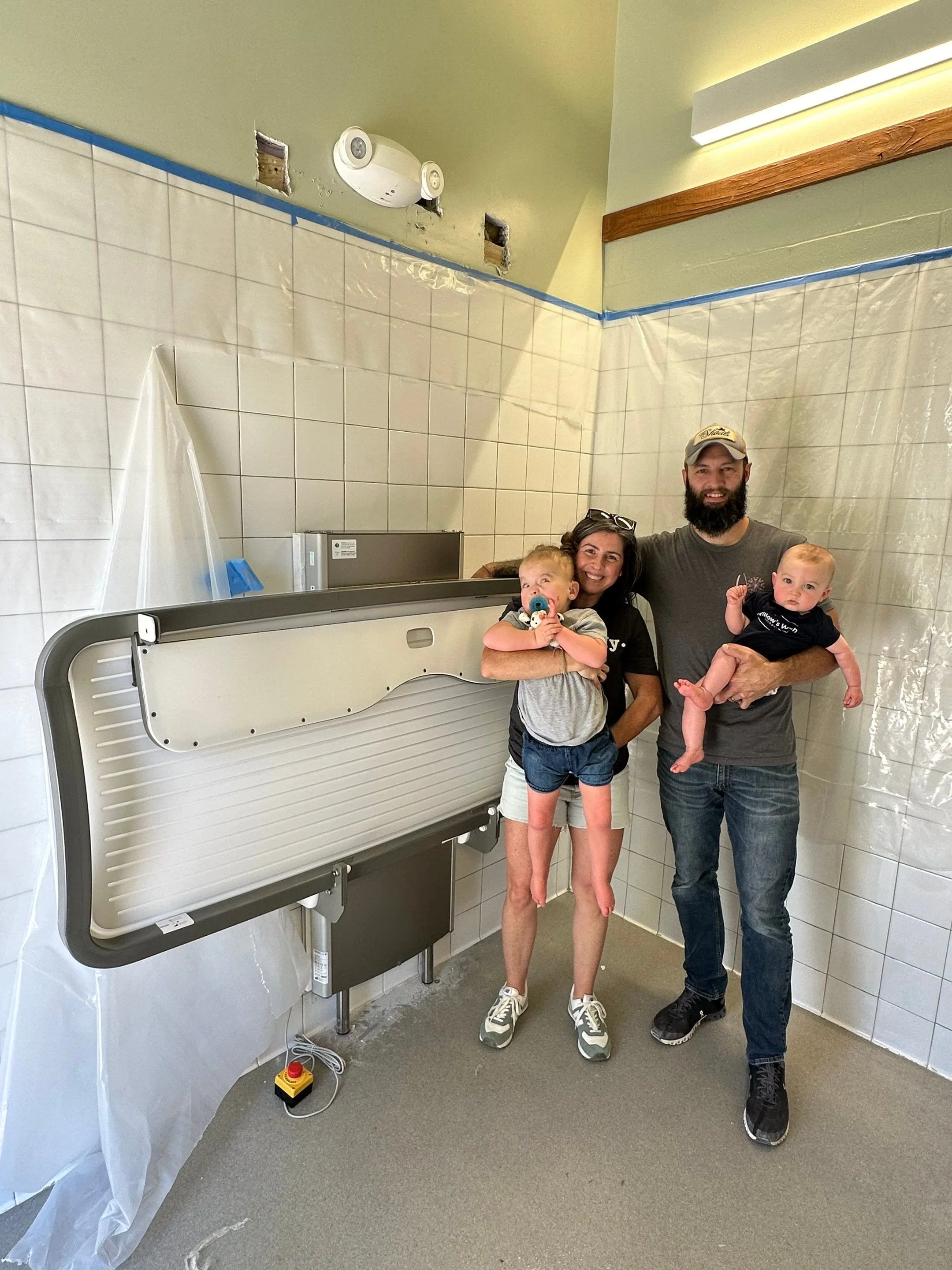 The Dail family standing next to a new powered changing table provided by Willow's Wish Foundation