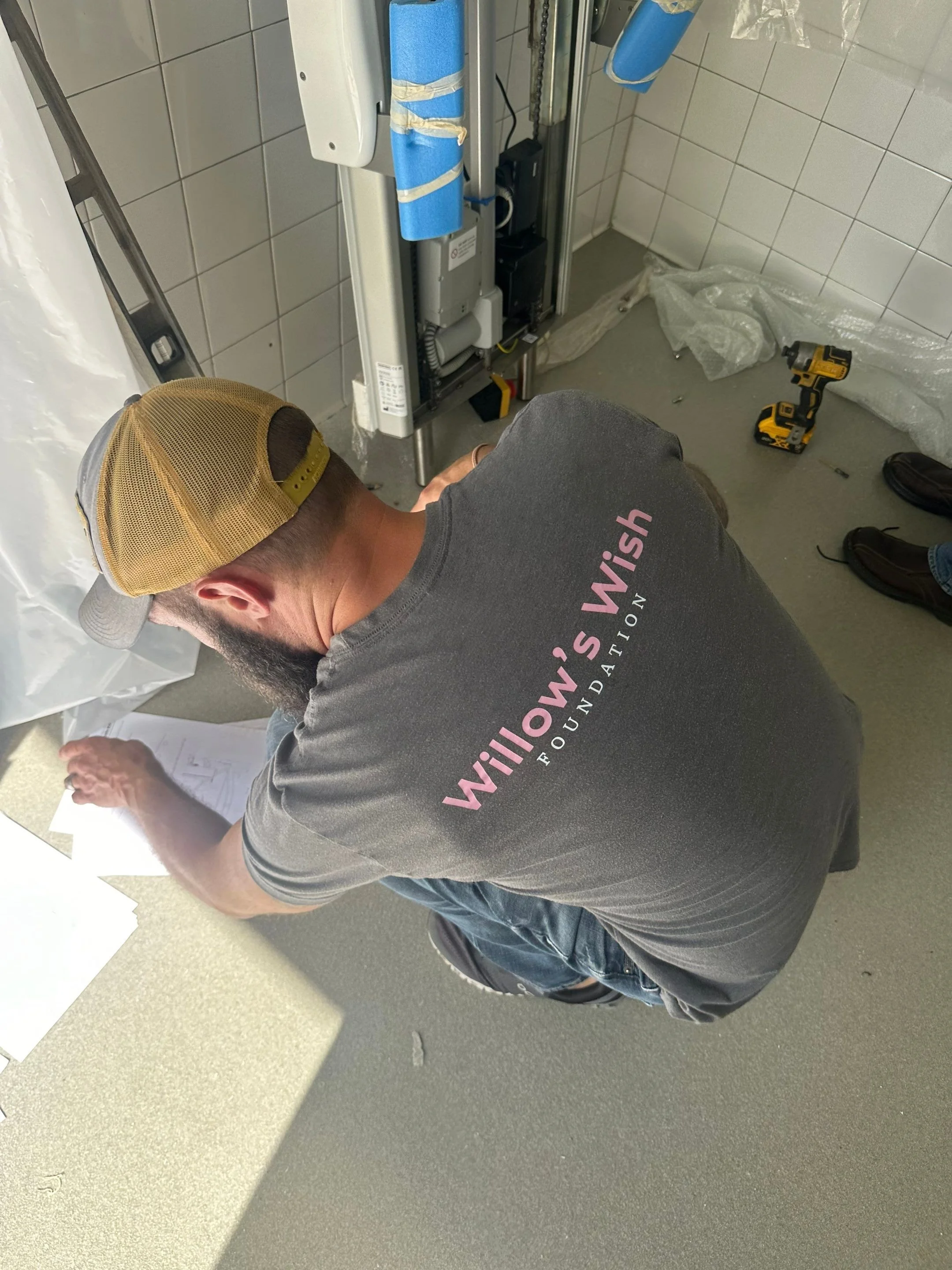 Mark Dail wearing a Willow's Wish Foundation shirt while installing a powered changing table.