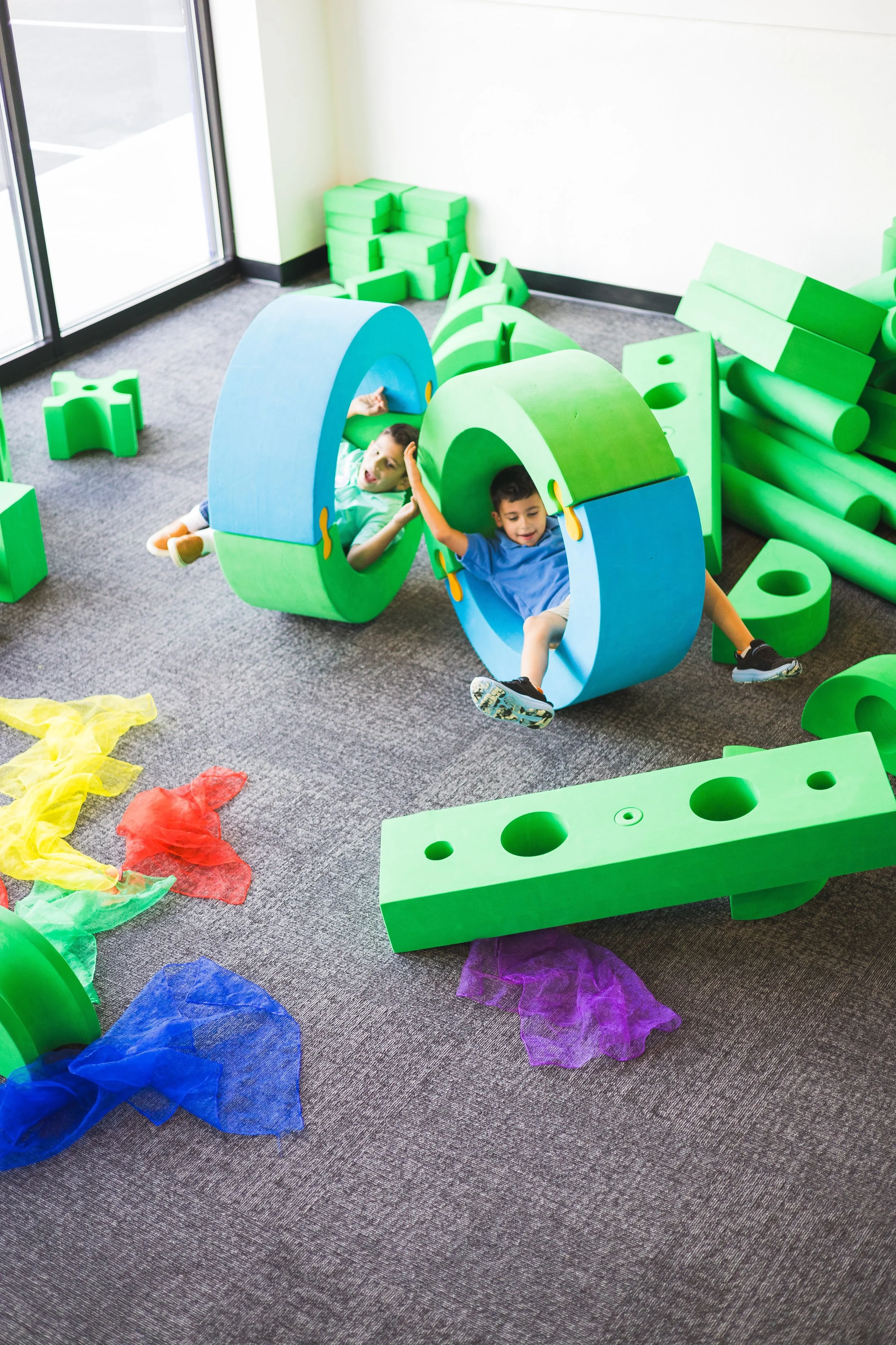 Children playing with large green and blue blocks