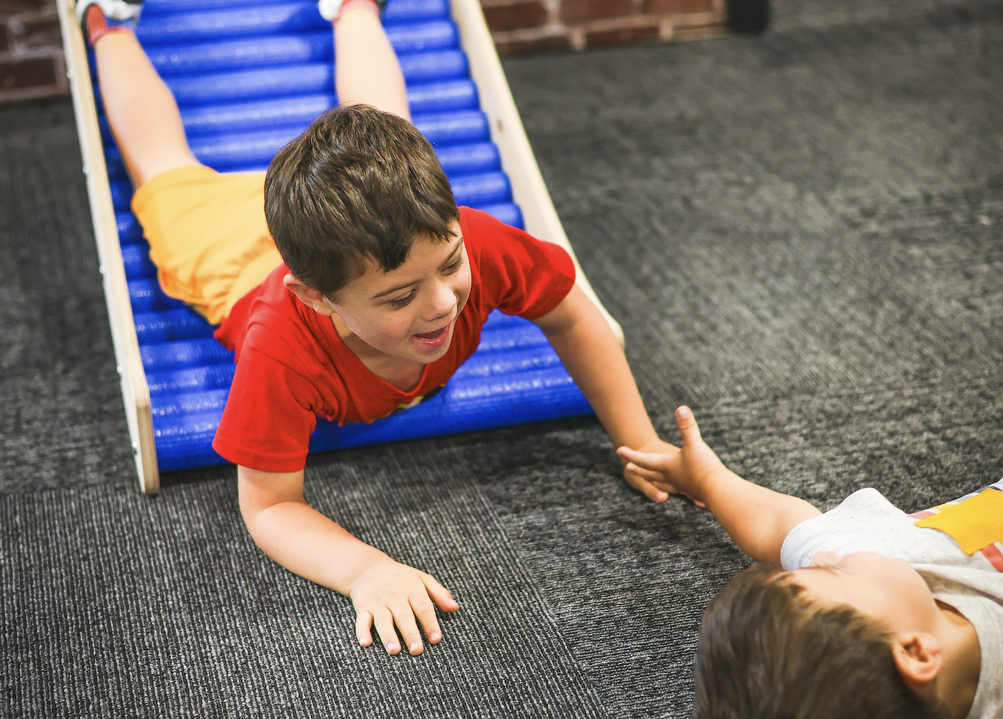 Two little boys play together on the rolling slide at the Museum