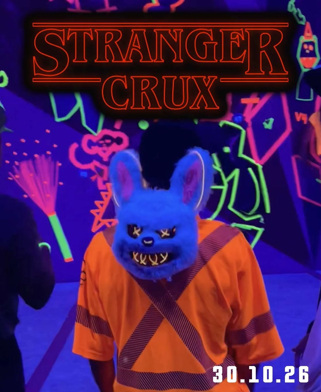 Person portant un masque de loup avec un costume orange dans une pièce au décor néon. La scène est sombre avec des lumières fluorescentes colorées et un texte en anglais "Stranger Crux" en haut.