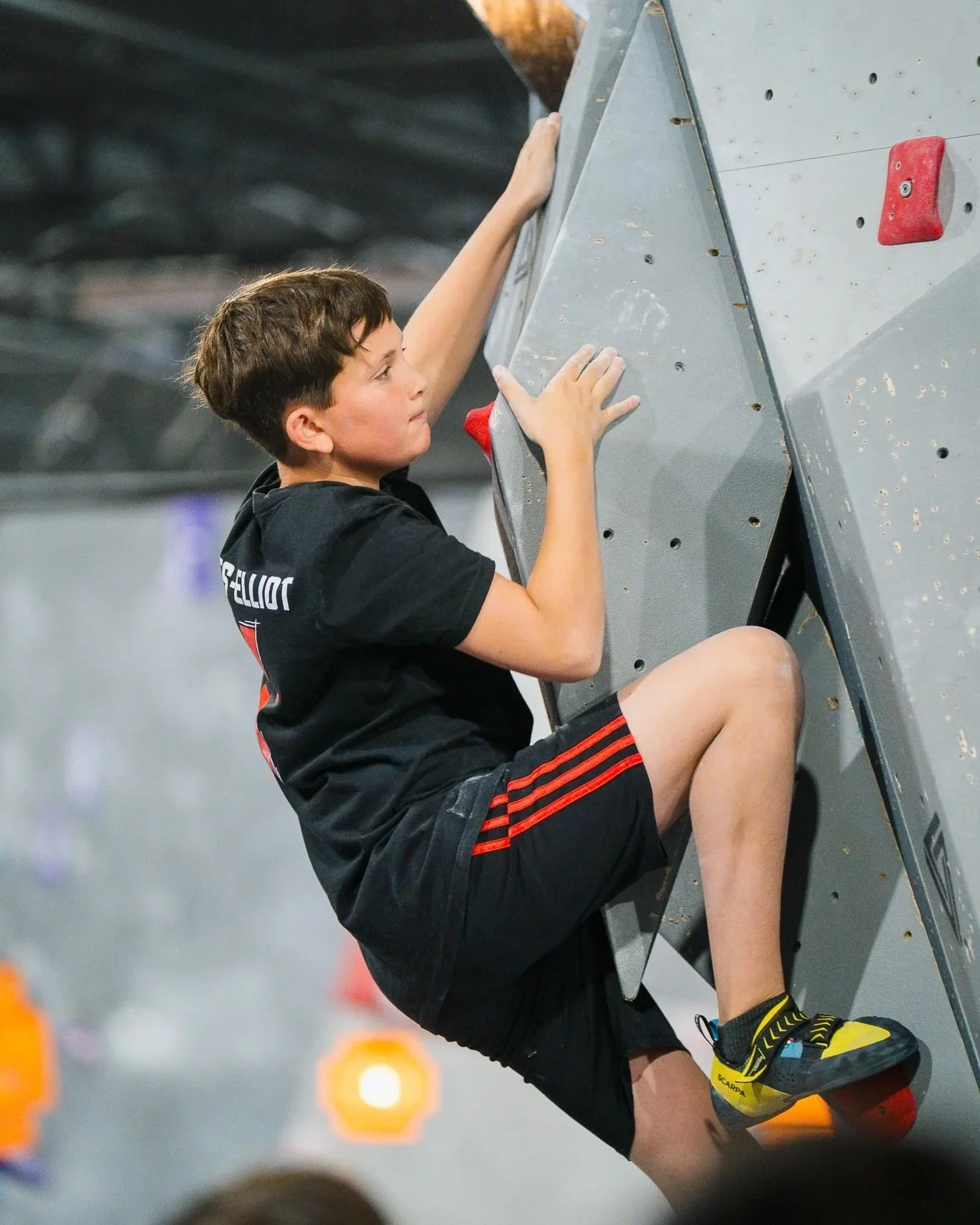 Petit garçon qui fait des cours d'escalade sur les murs de blocs au Le Crux Laval