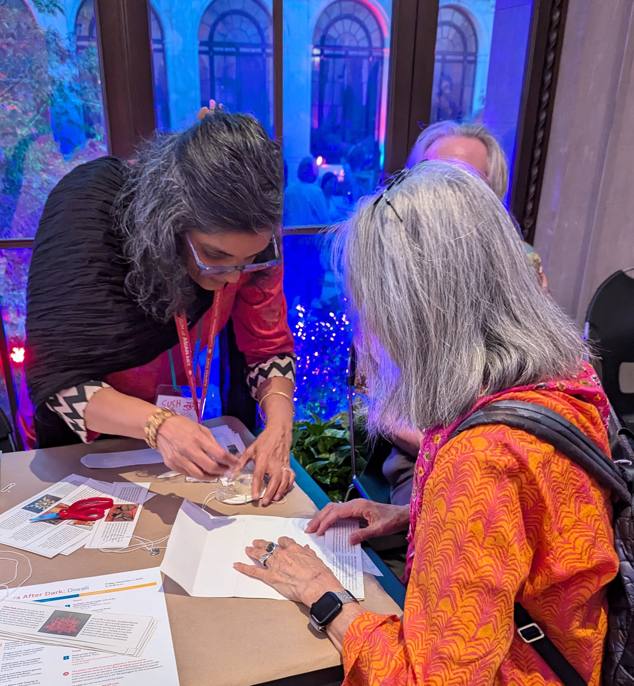 Sush shows Gail how to make the book. Both are docents at the NMAA.