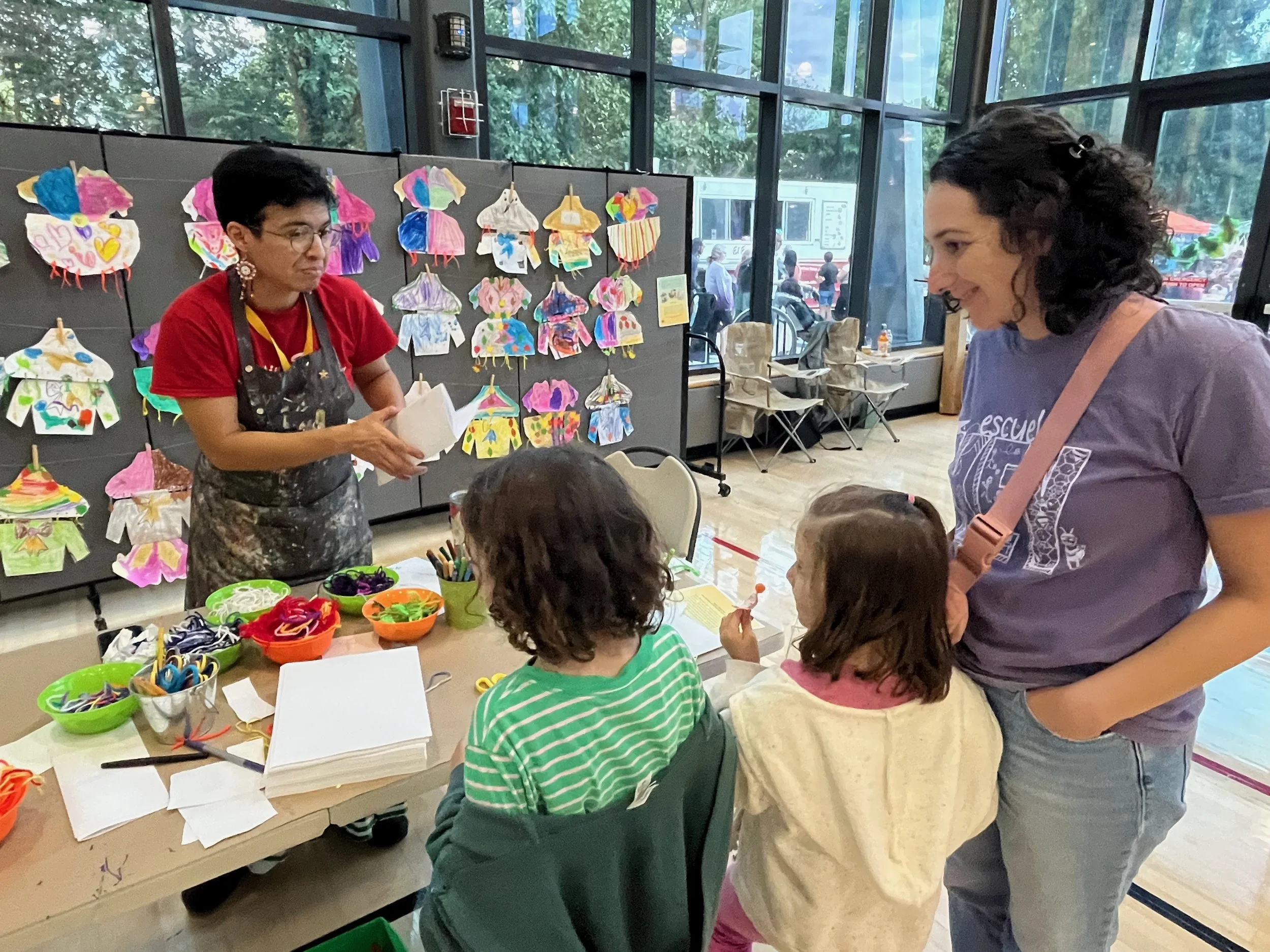 Girasol O'Neill teaches the Jalisco Dress activity with his students' creations on display behind him