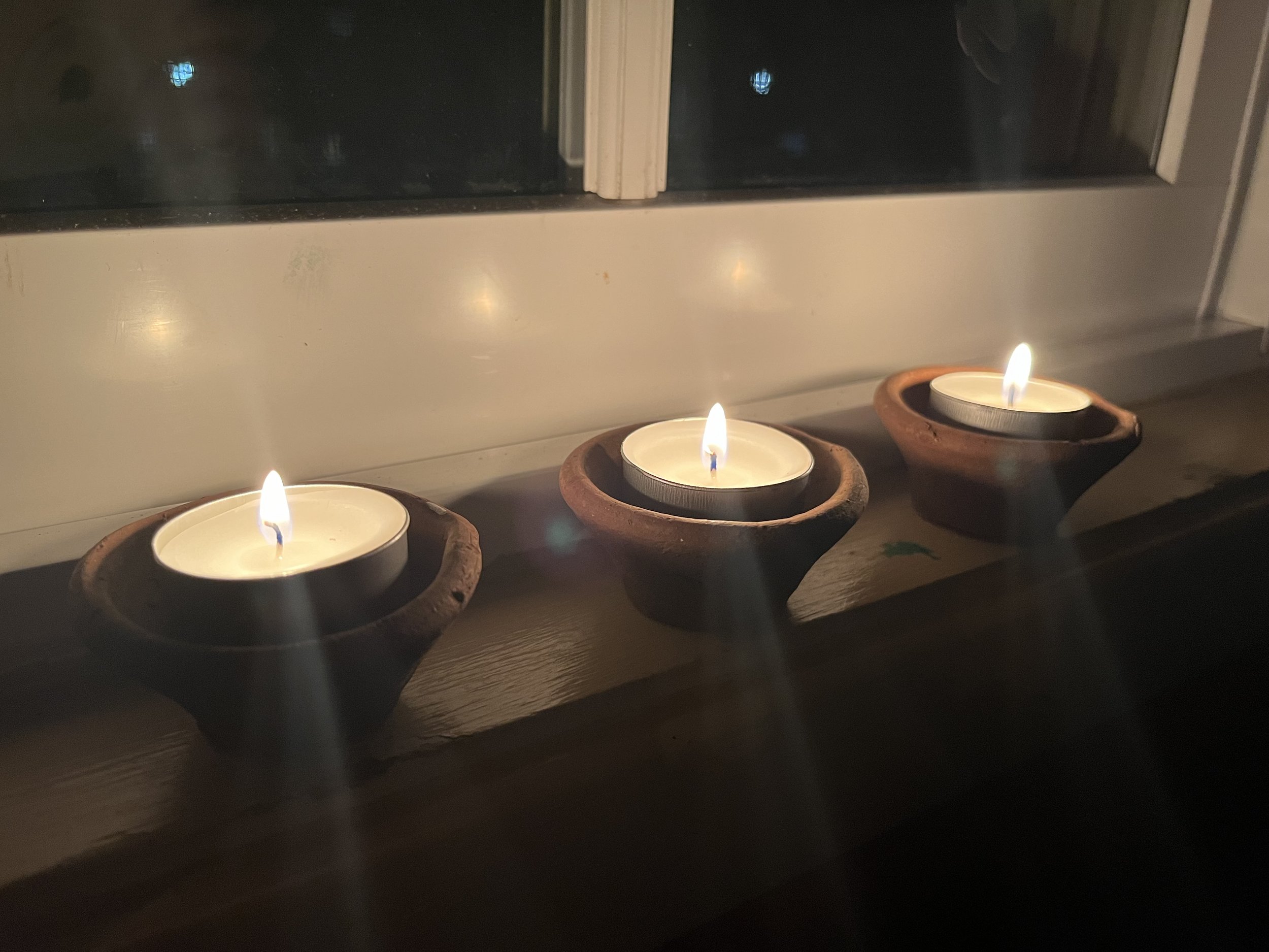 Diyas or clay lamps on the window in my Studio. Here I use wax tealights because these ordinary and inexpensive clay diyas, traditionally filled with oil and a wick, would get ruined and then where would I get more? I would have to visit India during