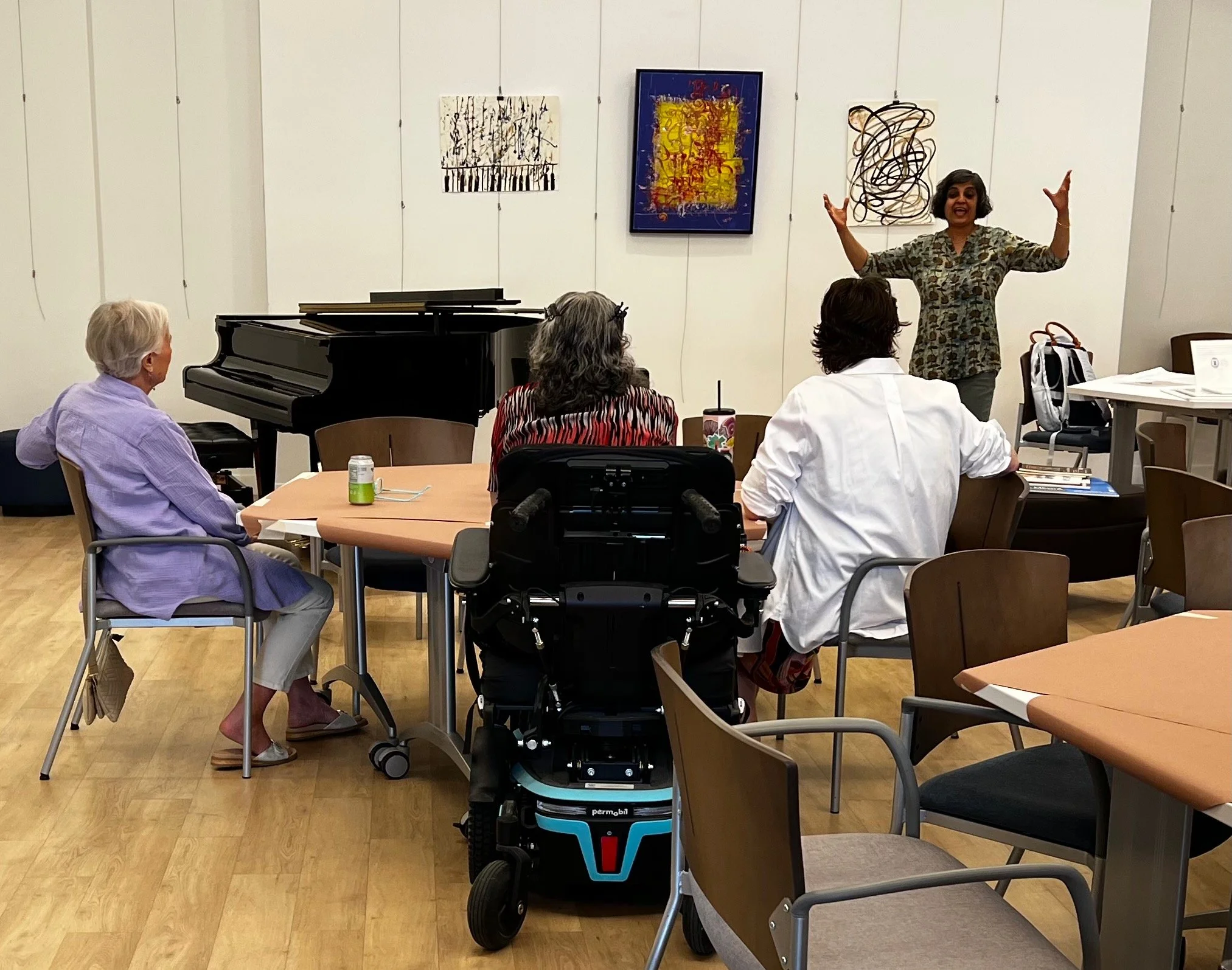Sushmita introduces the exhibit and how they curate a community art exhibit to the APC/Gilliam Place community. Examples of artworks by professional artists members of the Studio PAUSE community hang on the newly installed gallery system.