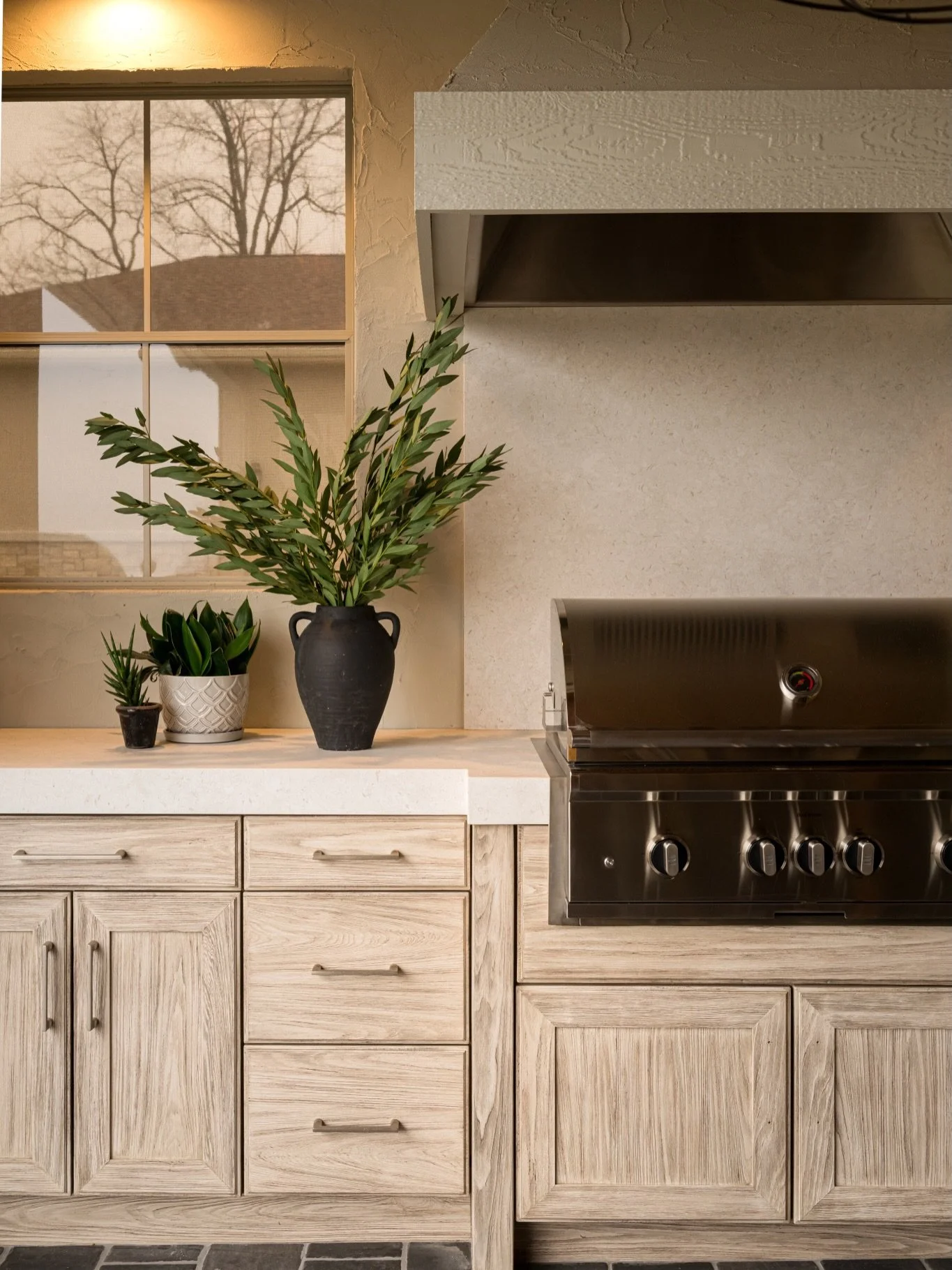 We designed this covered patio &amp; outdoor kitchen as a true extension of the home. The custom millwork grounds the grill station, while the stucco hood softens the architecture. 

Layered neutrals carry through from the countertop by @cosentinousa