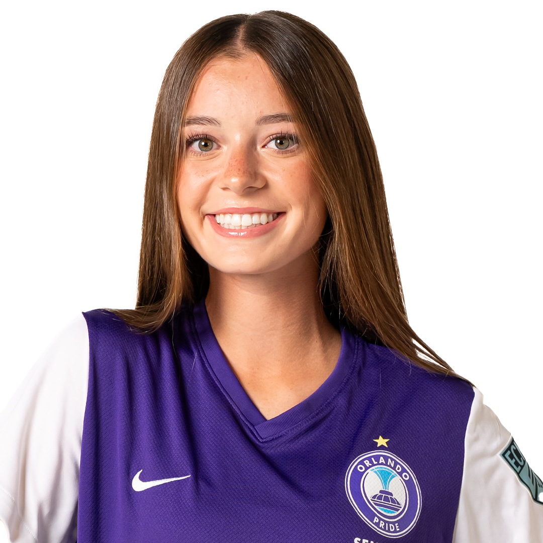 Young woman with long brown hair smiling, wearing a purple and white Orlando Pride soccer jersey.