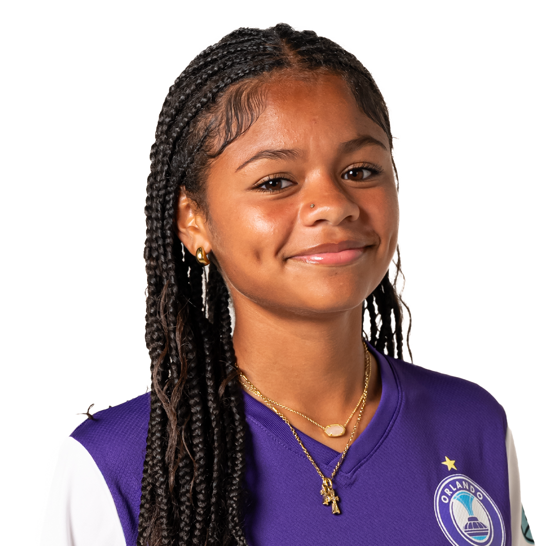 Portrait of a young girl with braided hair wearing a purple and white Orlando soccer jersey, smiling at the camera.