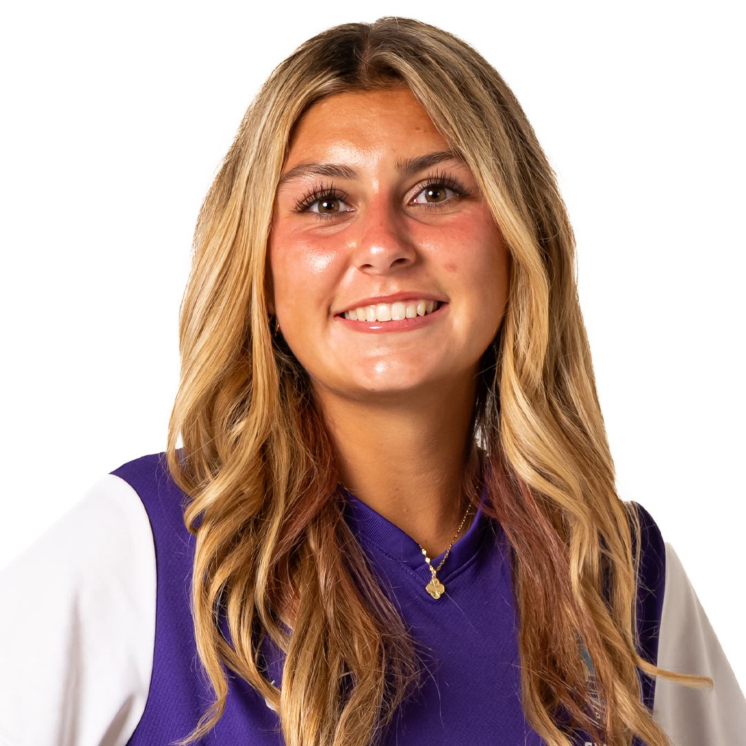 Close-up of a young woman with long blonde hair, smiling, wearing a purple and white sports jersey, and a gold necklace.