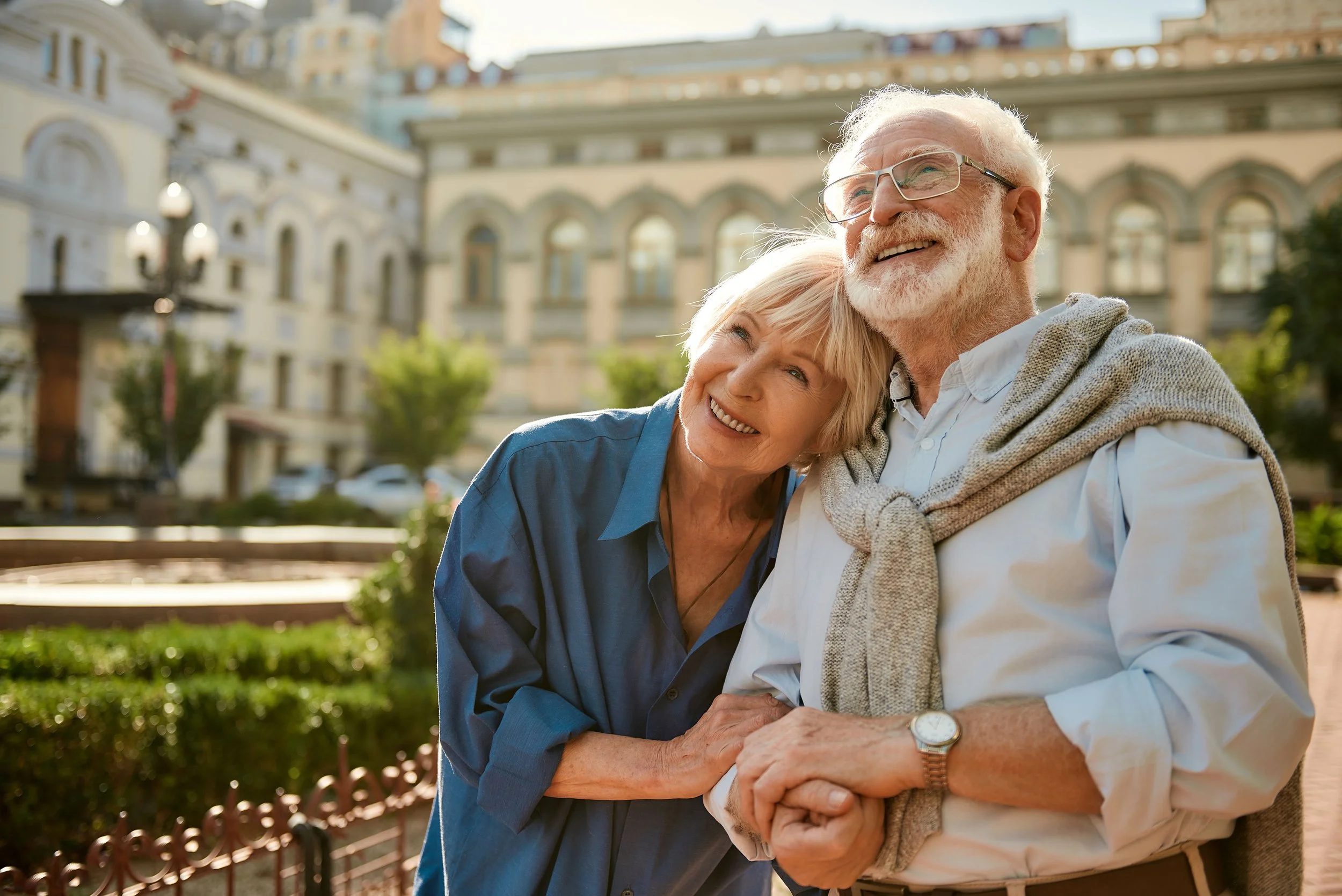 Elderly couple smiling and holding hands as they take in the views in Europe