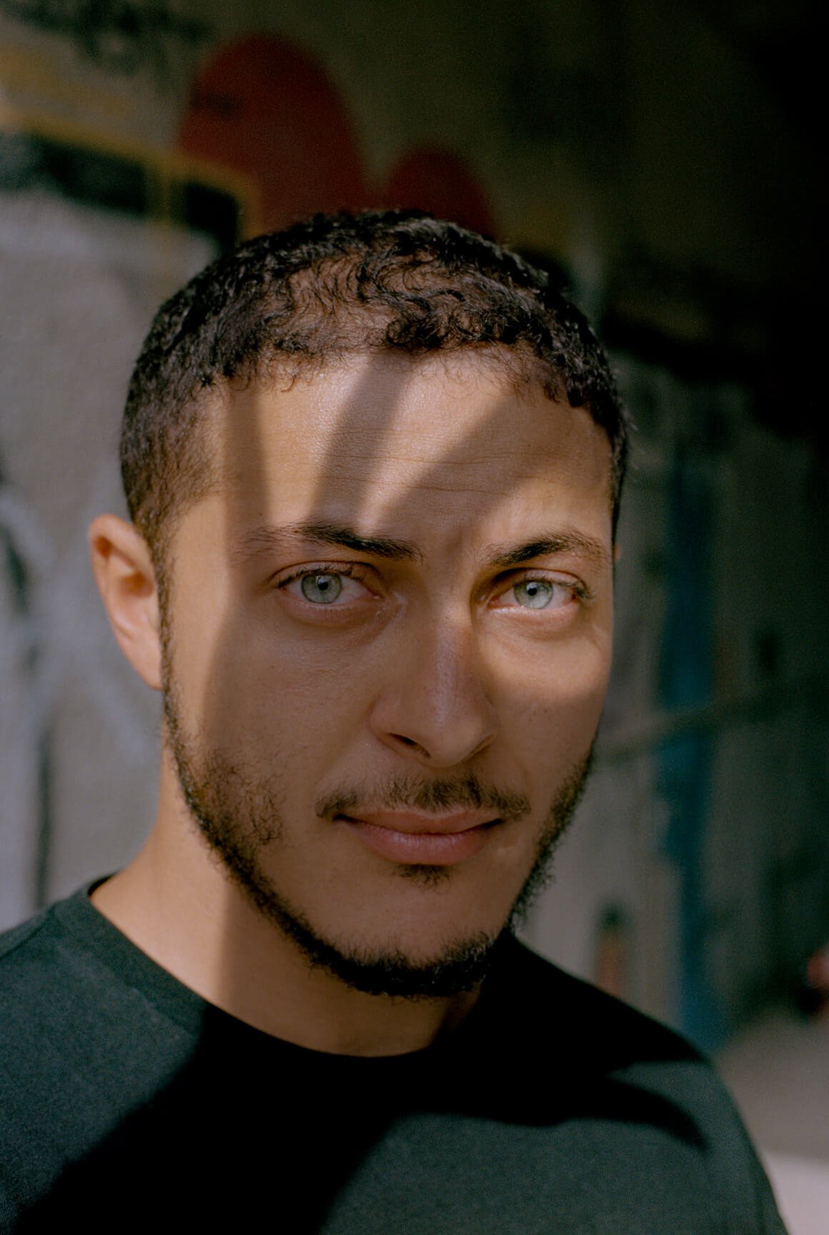 Un portrait d’un Tunisien aux yeux bleus, dont le visage est recouvert d’une ombre en forme de main.