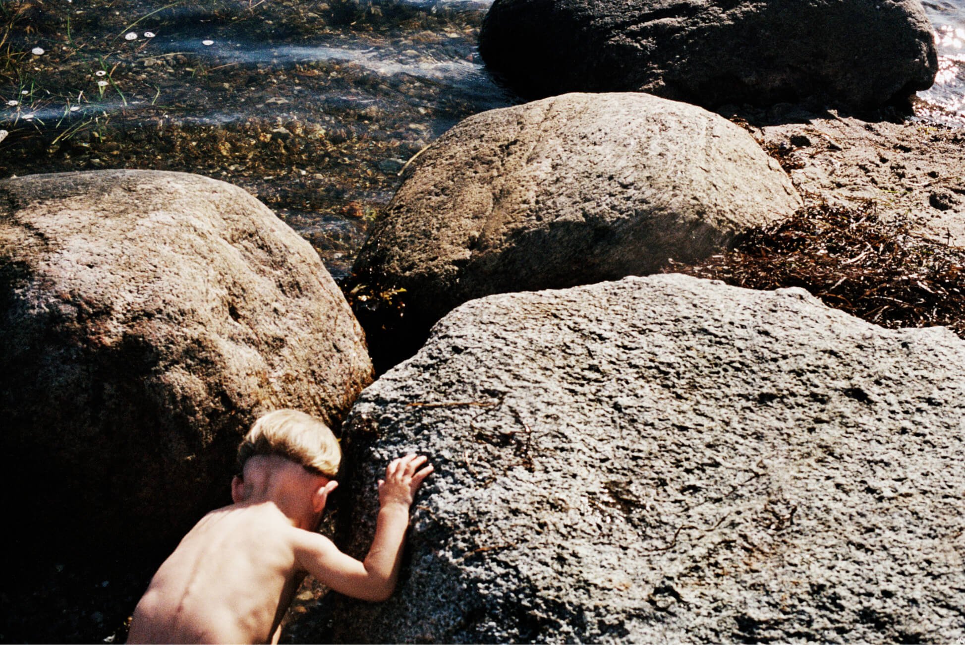 Ein kleines Kind spielt auf Felsen im Wasser.