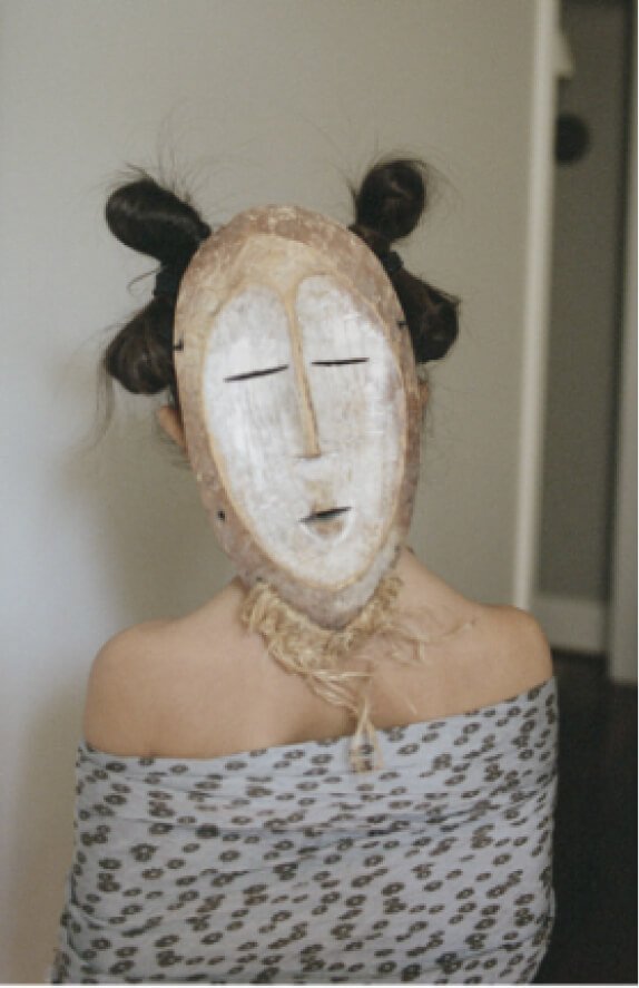 Ein junges Mädchen, das eine Stammesmaske trägt.