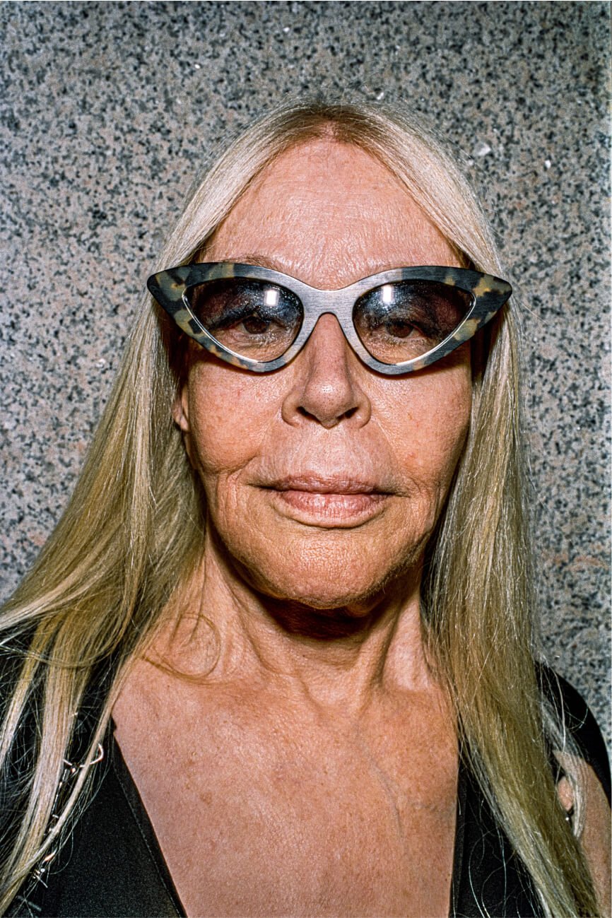 Porträt einer blonden Frau mittleren Alters mit eckiger Schildpattbrille.