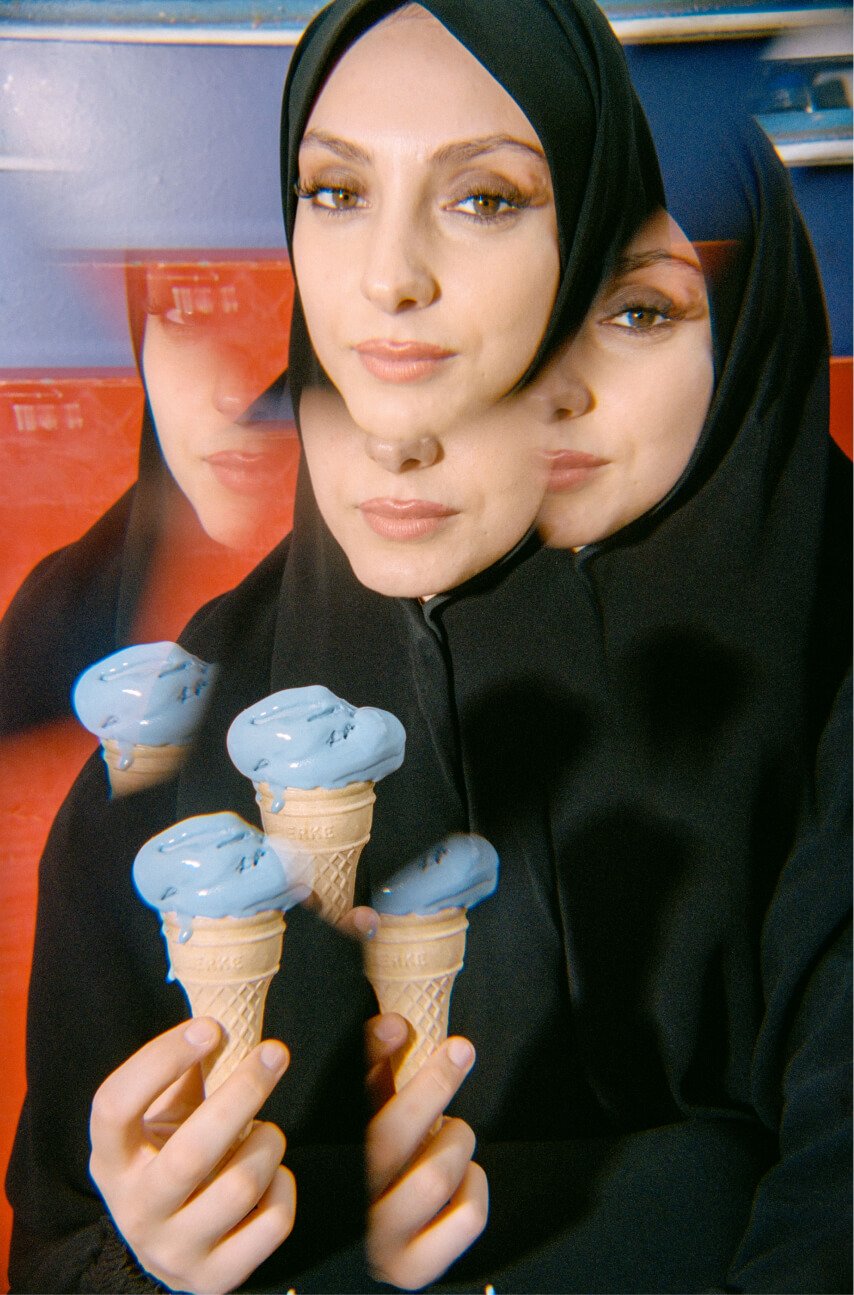 Una donna coperta di velo duplicata in piedi con un cono gelato.