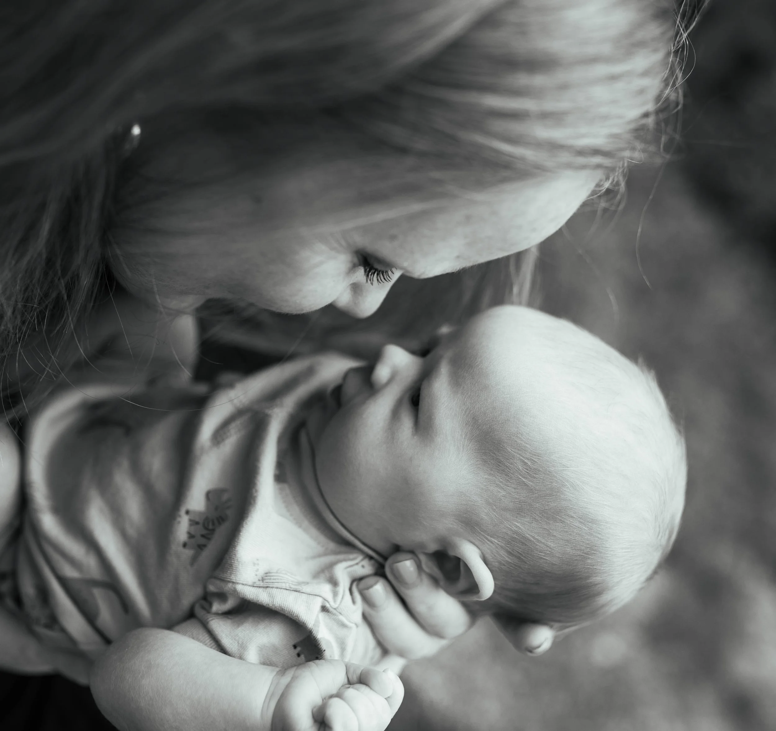 Black and white photo of a woman tenderly holding and looking at a baby in her arms.