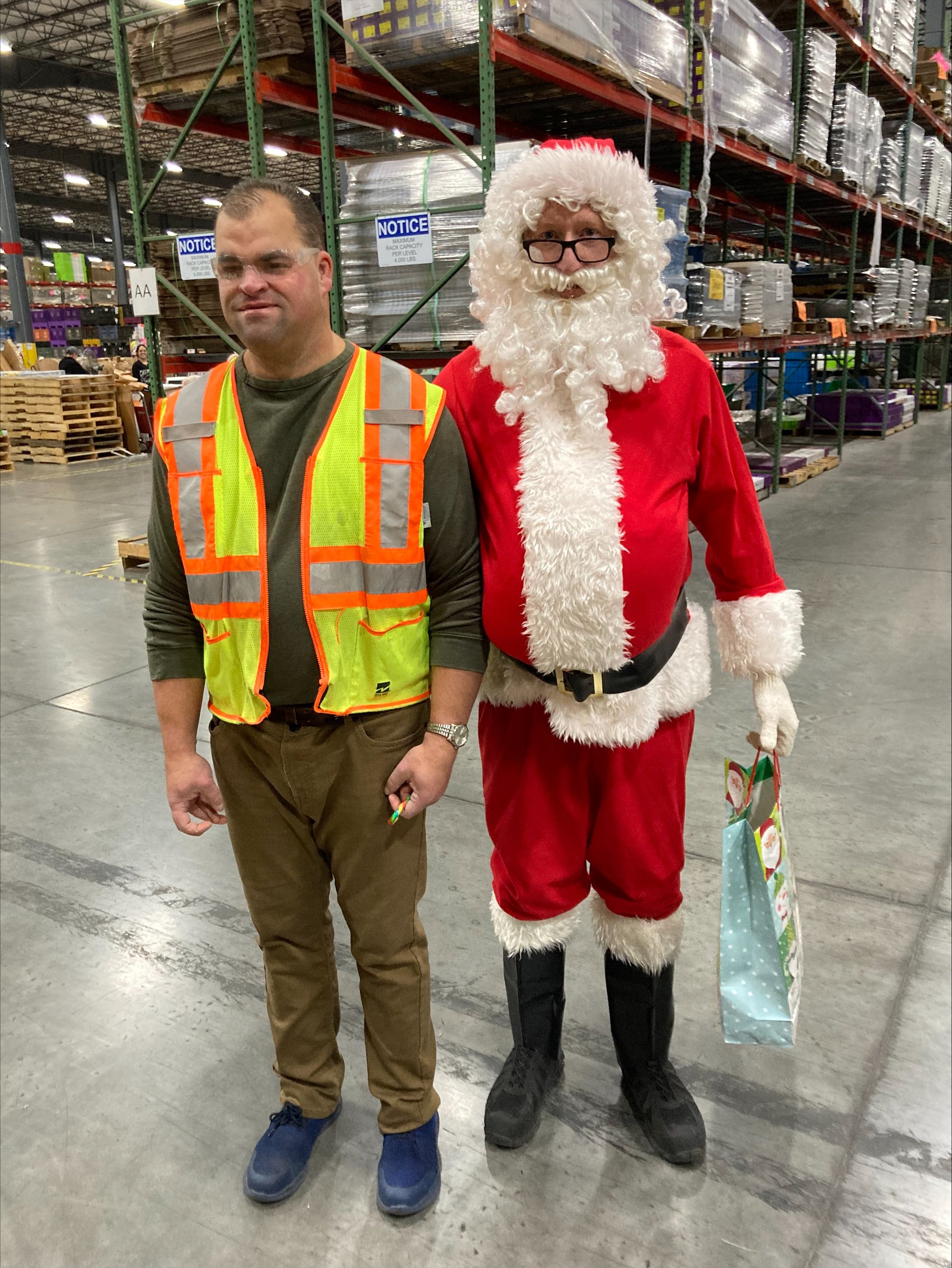 NW Works service recipient, Steve, stands with Santa in Trex's warehouse