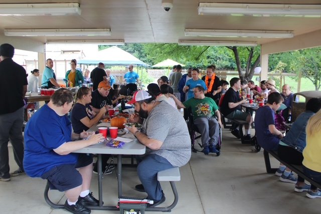  A large group of people is shown eating under the NW Works pavilion outdoors. 