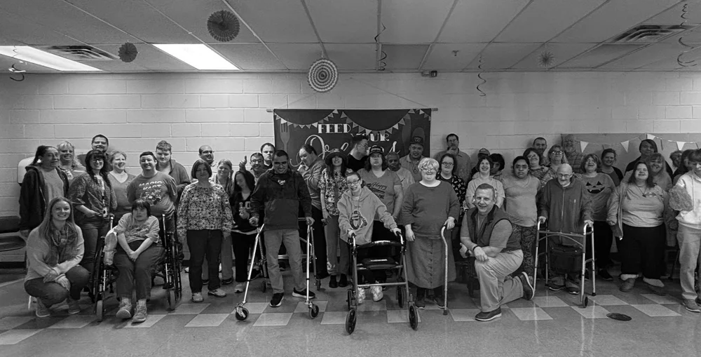  A large group of participants at NW Works smile and stand for a photo. The photo is in black and white. 